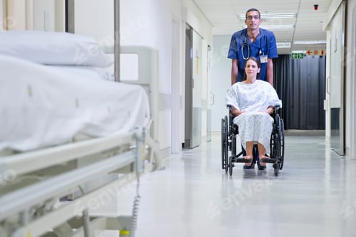 Preview: Male Nurse Pushing Patient Along Hospital Corridor In Wheelchair