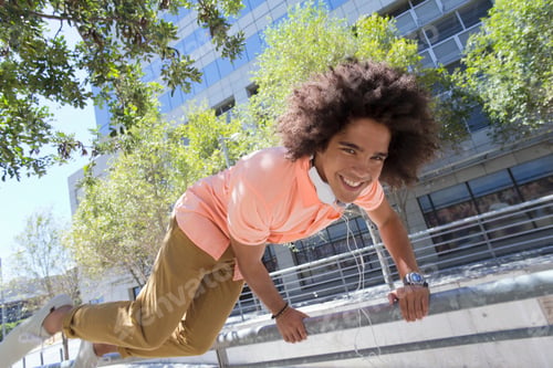 Preview: Close Up Of A Smiling Young Man Jumping Over A Railing In The City