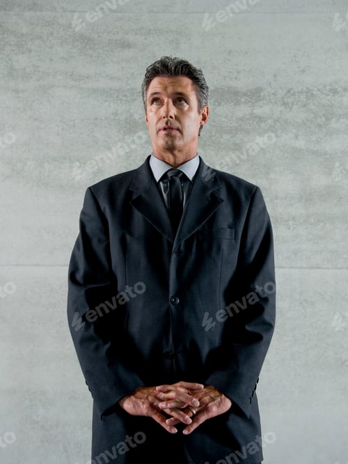 Preview: A Mature Businessman Standing With Hands Clasped, Looking Upwards