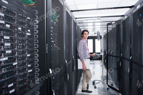 Preview: Wide Shot Of A Young Technician Looking At The Camera While Working On A Computer Connected To A