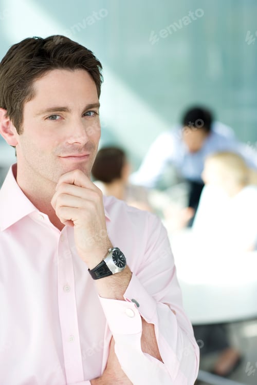 Preview: A Businessman In An Office, Three Colleagues In Background Having A Discussion