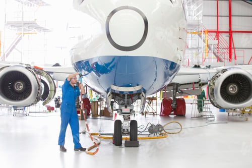 Preview: Wide Shot Of An Engineer Connecting Wires To A Passenger Jet At A Hangar.