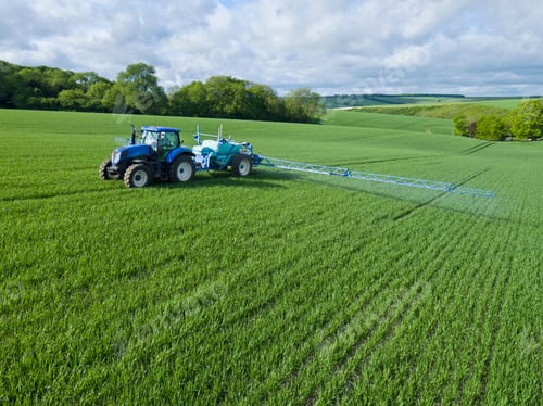 Preview: Tractor Spraying Crop In Green Farm Fields With Pesticide