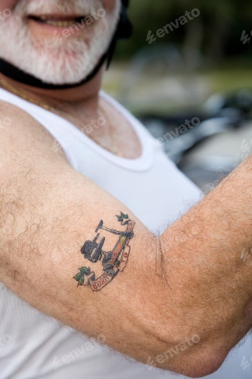 Preview: Man Shows Arm Tattoo with Bold Design