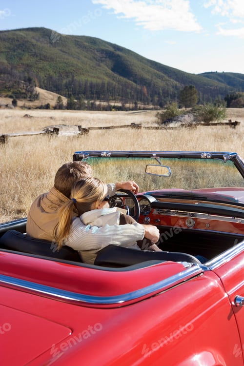 Preview: Loving Mature Couple Driving Classic Red Convertible Car On Road Trip