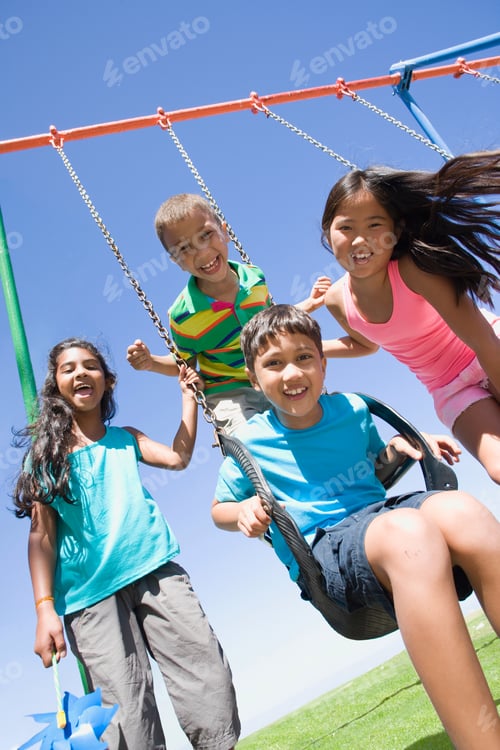 Preview: Vertical Shot Of Children Smiling Together At A Swing Set On A Playground