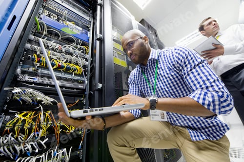 Preview: Close Up Of Technicians With A Laptop And A Digital Tablet Checking Server In The Data Center