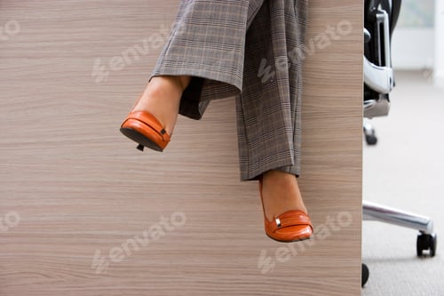 Preview: Close-Up Shot Of A Businesswoman Wearing Checked Grey Trousers And Orange High Heels, Sitting On