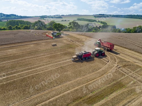Preview: Aerial View Of Tractor Pulling Baler Making Straw Bales In Harvested Wheat Field And Combine