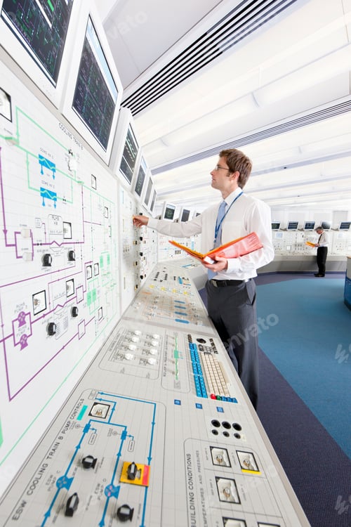 Preview: Vertical Shot Of A Young Engineer With A File Adjusting Controls While Looking At A Computer Screen