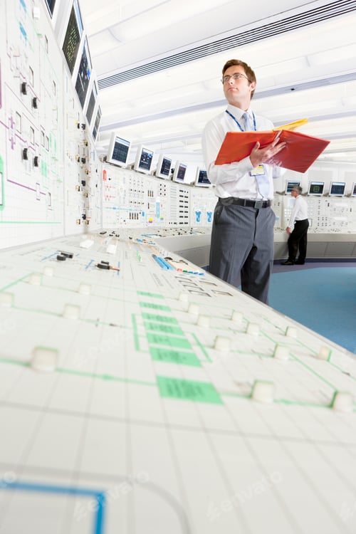 Preview: Low-Angle Shot Of A Young Engineer With A File Looking At A Computer Screen In The Control Room Of