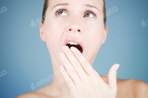 Preview: A Young Woman Yawning In Front Of A Blue Wall
