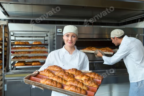 Preview: Smiling Baker Holding A Tray Of Breads In The Bakery Kitchen