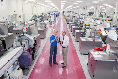 Preview: Wide Shot Of An Engineer And A Businessman Standing In The Aisle Of A Manufacturing Plant While