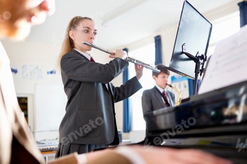 Preview: High School Student Reading Sheet Music And Playing A Flute With A Music Teacher Playing Piano In