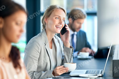 Preview: Smiling Business Woman Sitting At Her Desk Holding A Cup Of Coffee And Talking On A Cell Phone