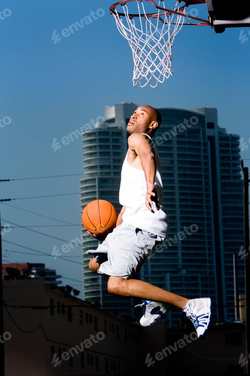 Preview: Young African American Man Jumping With A Basketball On An Urban Basketball Court