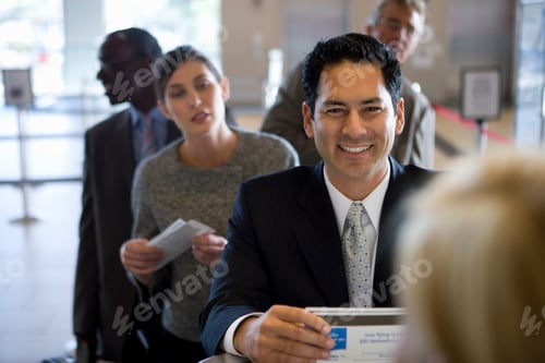 Preview: Businessman With Ticket On Trip Checking In At Airport Desk
