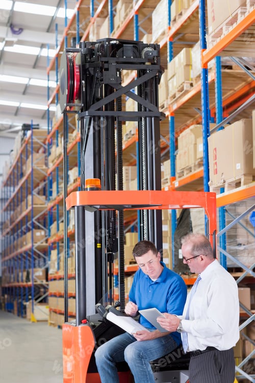 Preview: Vertical Wide Shot Of A Worker Discussing Paperwork With A Supervisor Standing Next To A Forklift
