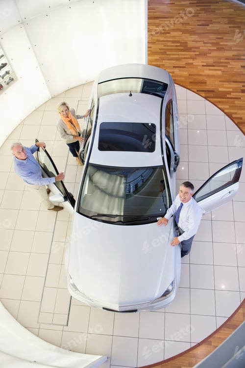 Preview: Top View Portrait Of Salesman And Couple Looking Inside Car In A Car Dealership Showroom