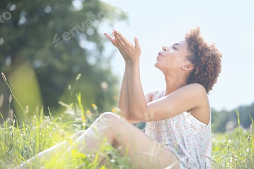 Preview: Young Woman Blowing Seeds As She Sits In Countryside