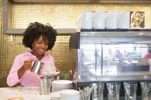 Preview: Portrait Of A Smiling Waitress Pouring A Cup Of Coffee At A Coffeeshop