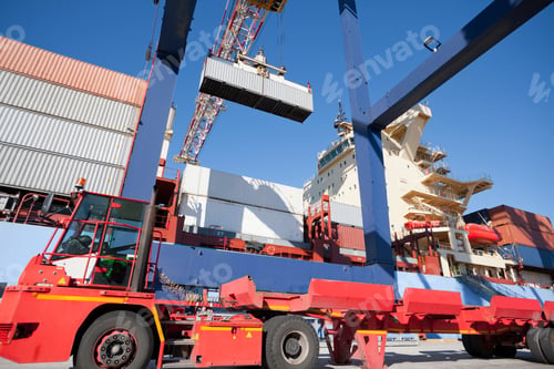 Preview: Low Angle Shot Of A Lorry Standing Under A Gantry Crane Ready To Be Loaded With A Cargo Container