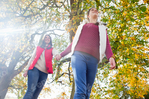 Preview: Low-Angle Shot Of A Mother And Daughter Holding Hands And Walking Through An Autumnal Forest.