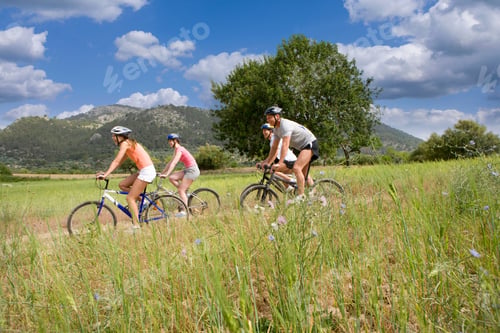 Preview: Active Couples Wearing Helmets Riding Bikes In Countryside Together