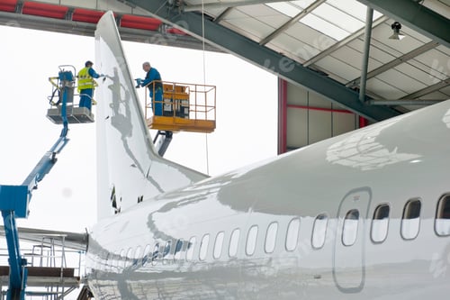 Preview: Engineers On Hydraulic Lifts Inspecting The Tail Of A Passenger Jet At A Hangar.