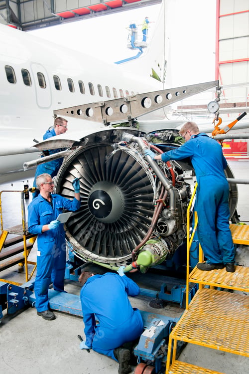 Preview: Vertical Wide Shot Of Engineers Repairing The Engine Of A Passenger Jet At A Hangar.