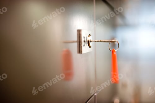Preview: Close-Up Of A Key On Red Key Ring Hanging From Lock On Door As Seen From Side.