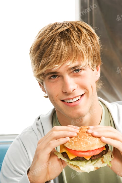 Preview: Teenage Boy Eating A Large Hamburger In A Diner