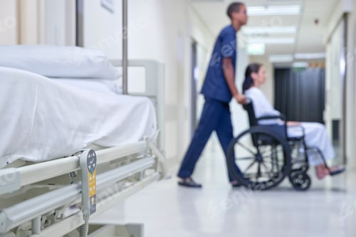 Preview: Male Nurse Pushing Patient Along Hospital Corridor In Wheelchair