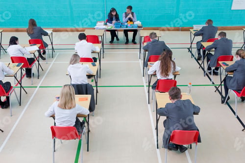 Preview: Teachers Supervising Middle School Students Taking Examination At Desks In School Gymnastics Hall