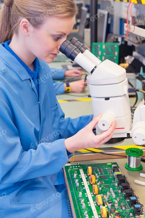 Preview: Female Technician In An Apron Using A Microscope To Examine A Circuit Board In A Manufacturing