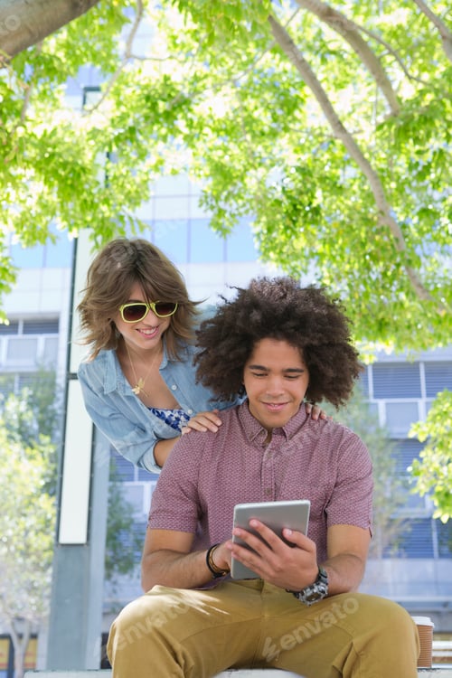 Preview: Smiling Young Couple Watching Something On A Digital Tablet In An Urban Park