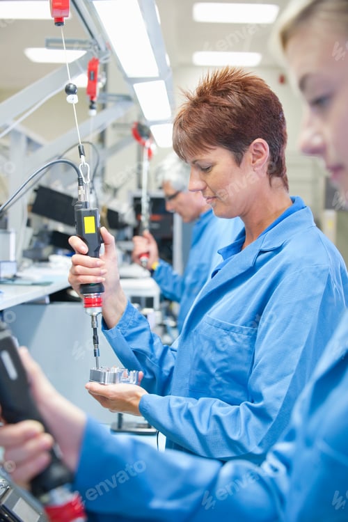 Preview: Vertical Shot Of Technicians In Aprons Using Electric Screwdrivers To Assemble Machine Parts On