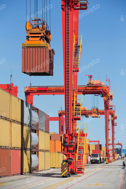 Preview: Vertical Shot Of A Gantry Crane Holding A Cargo In The Air At A Dockyard