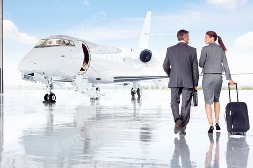 Preview: Smiling Businesswoman And Businessman Walking Towards A Private Jet