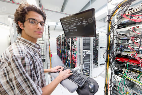 Preview: Technician Looking At The Camera While Working On A Computer In A Server Room At A Data Center.