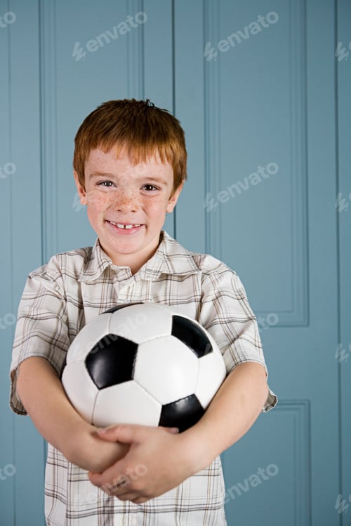 Preview: Boy With Ginger Hair Smiling And Holding Football
