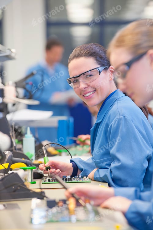 Preview: Vertical Shot Of Female Technician Smiling At The Camera While Soldering Circuit Boards On