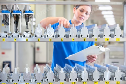 Preview: Female Technician With A Clipboard Checking Machine Parts In An Inventory Shelf In A Manufacturing