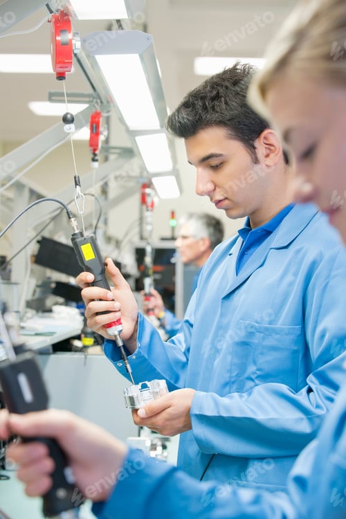 Preview: Vertical Shot Of Male Technician In Apron Using Electric Screwdrivers To Assemble Machine Parts On