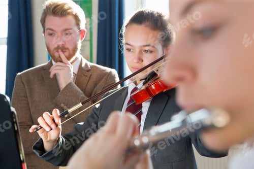 Preview: Teacher Watching High School Students Play Violin And Flute In A Music Class.