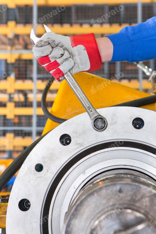 Preview: Close-Up Vertical Shot Of An Engineer'S Hand In Gloves Tightening Bolts Using A Wrench On A Gearbox