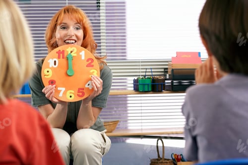 Preview: Horizontal Shot Of Children Learning To Tell The Time With Focus On Teacher Holding Colorful Clock