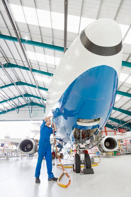 Preview: Vertical Wide Shot Of An Engineer Working On A Passenger Jet In A Hangar.