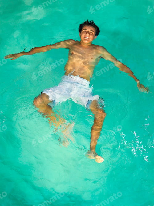 Preview: Top Angle Shot Of A Male Teenager Floating In A Swimming Pool.